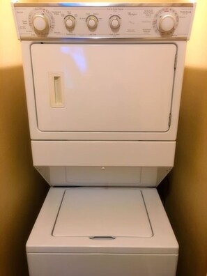 Une machine à laver à chargement frontal, de couleur blanche, dotée d’un panneau de commande avec plusieurs boutons et molettes.