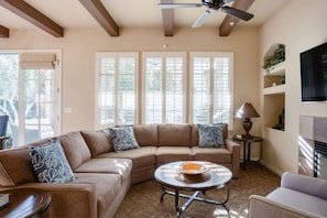 A living room with a sectional sofa, a round coffee table, and a ceiling fan. - Legacy Villas 2Br: PERFECT Spot w/Hotel Luxuries (La Quinta)