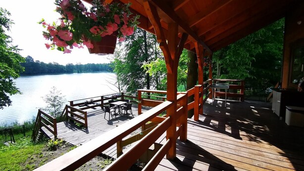 Una terraza de madera con asientos al aire libre con vistas a un lago.