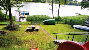Un parque con un área de juegos, mesas para picnic, un bote y un lago.