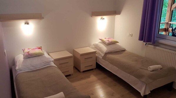 A small, cozy bedroom with two single beds, each with a nightstand and a lamp. - Domek uroczo położony we wsi Drynki, przy jeziorze Pozorty. Osada 4-ech domków (Maldyty)