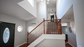 A spacious interior with a wooden staircase, a decorative door, and a skylight.