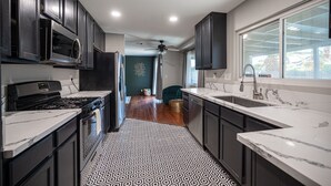 A modern kitchen with dark cabinets, a microwave, a stove, and a sink.