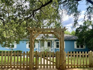 A wooden gate leading to a house with a blue exterior and white trim. - Cottage @ Midtown - Central Location! (Duplex) (Tallahassee)