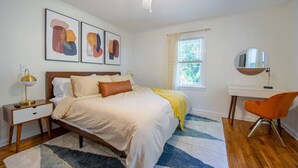 A bedroom with a bed, a desk, a chair, a ceiling fan, and artwork on the wall. - Cottage @ Midtown - Central Location! (Duplex) (Tallahassee)