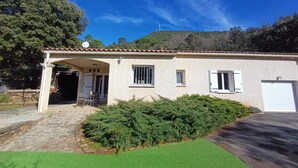 Une maison à deux étages, avec un toit en tuiles, une terrasse couverte et un garage.
