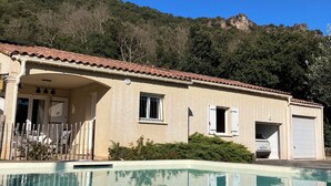 Une maison avec une piscine, un garage et une vue sur les montagnes.