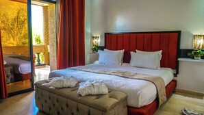 A hotel room with a large bed, a red headboard, a wooden bench, and a view of the outdoors. - Luxury heated pool Villa Marrakech (Marrakech)