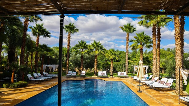 A pool area with lounge chairs and palm trees. - Luxury heated pool Villa Marrakech (Marrakech)