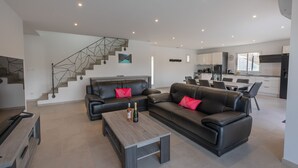 Un salon moderne avec un canapé, une table basse et un escalier menant à une cuisine.