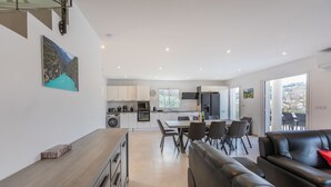Une cuisine moderne avec des meubles blancs, un coin repas comprenant une table et des chaises, et un canapé en cuir noir.