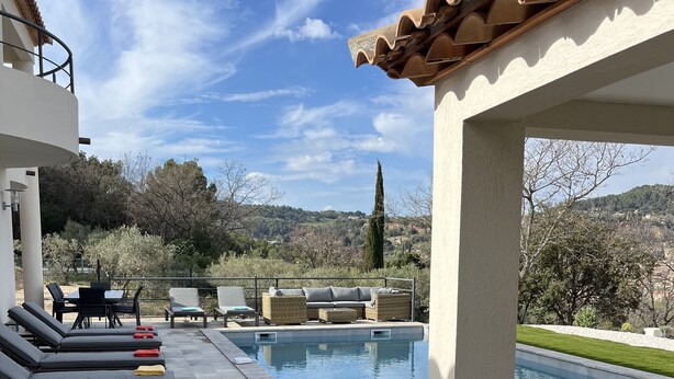Un espace aménagé au bord de la piscine, avec des chaises longues et une vue sur le paysage environnant.