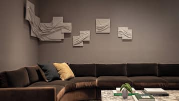 A modern living room with a dark brown sectional sofa, a marble coffee table, and abstract wall art.
