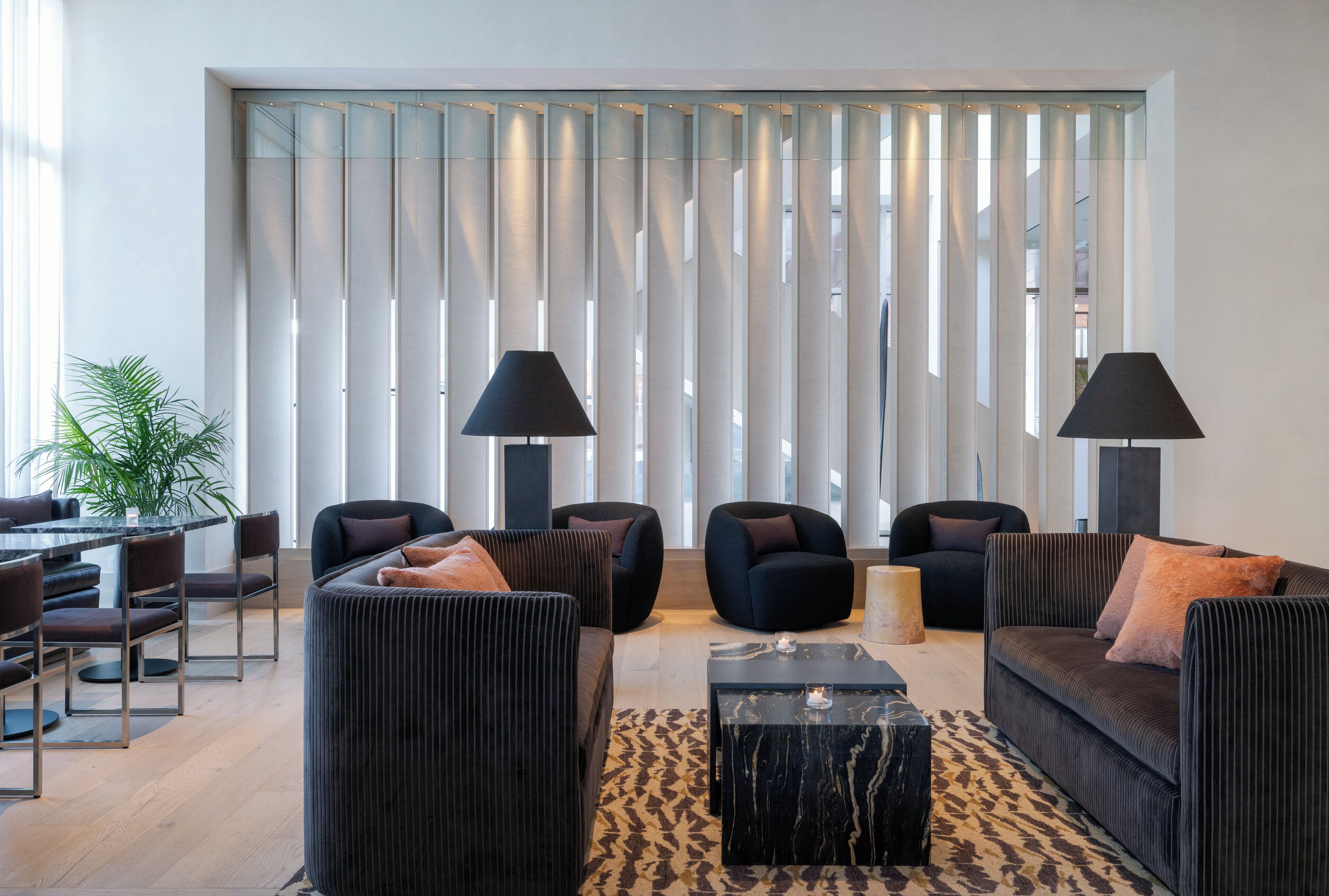 A modern living room with a sofa set, two armchairs, a coffee table, and a dining area with chairs and a table.