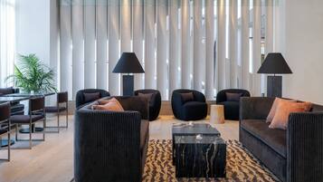 A modern living room with a sofa set, two armchairs, a coffee table, and a dining area with chairs and a table.
