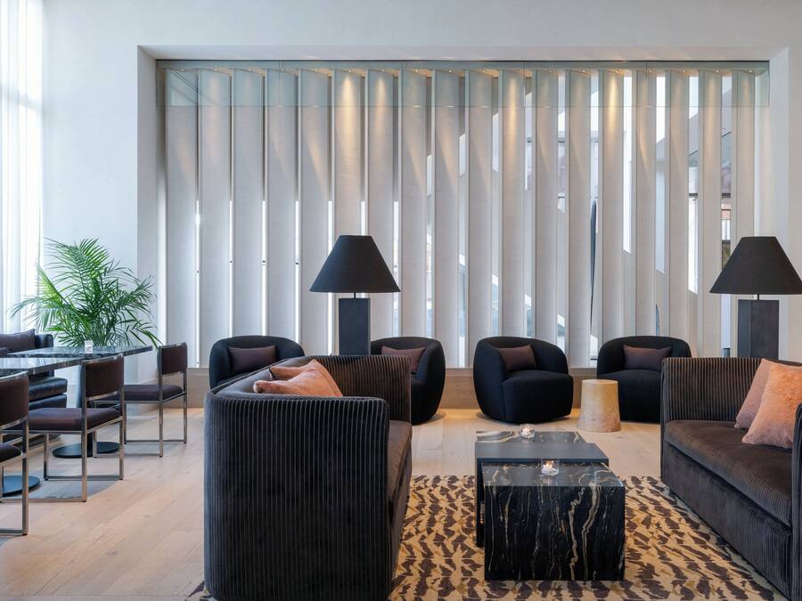 A modern living room with a sofa set, two armchairs, a coffee table, and a dining area with chairs and a table.