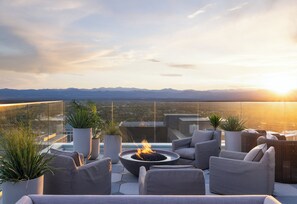 A rooftop terrace with a fire pit, seating area, and potted plants. - Kimpton Claret Hotel by IHG (Denver)