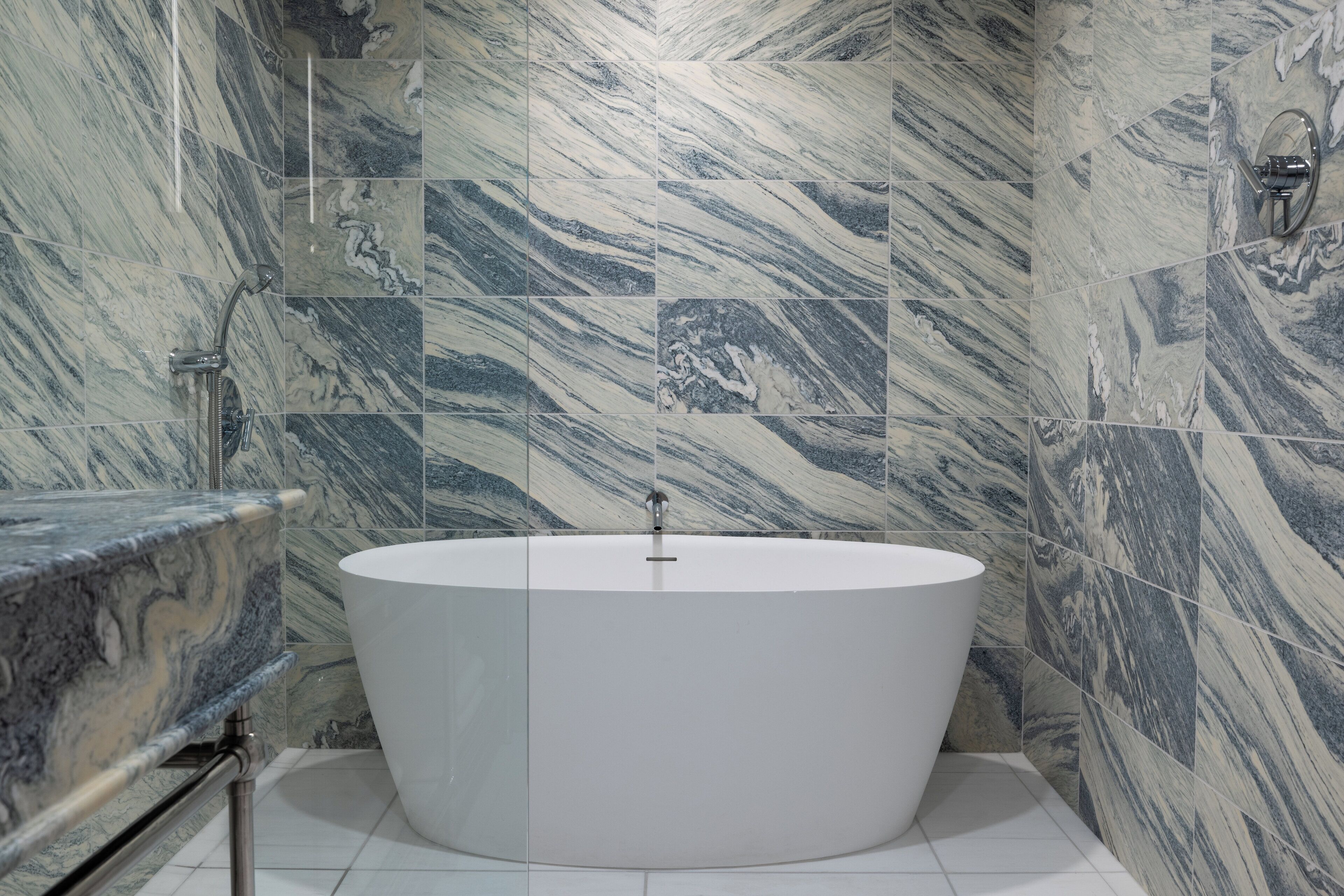 Un baño moderno con una bañera independiente, baldosas de mármol y encimera de mármol.