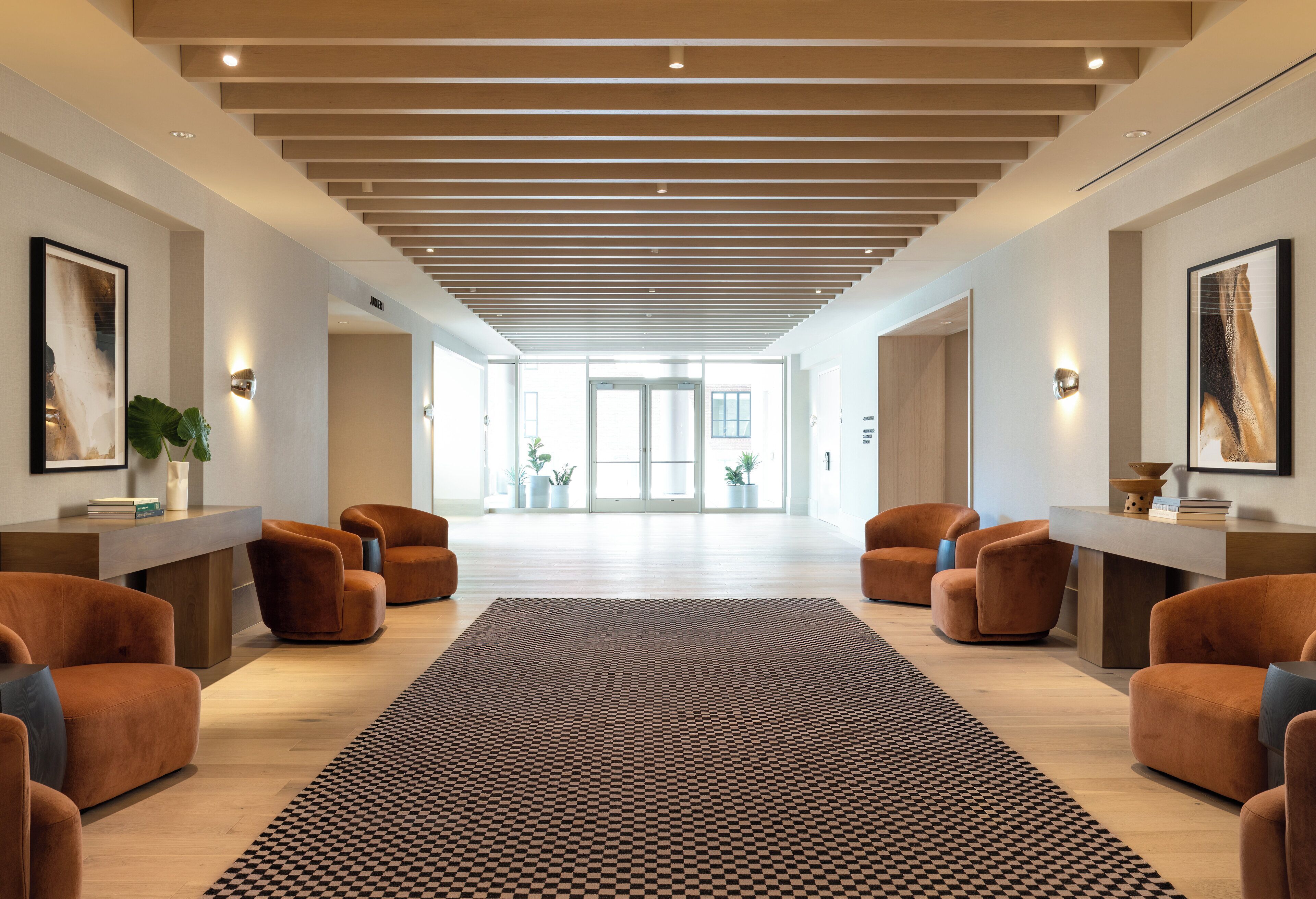 A spacious lobby with a checkered rug, wooden ceiling, and modern furniture.