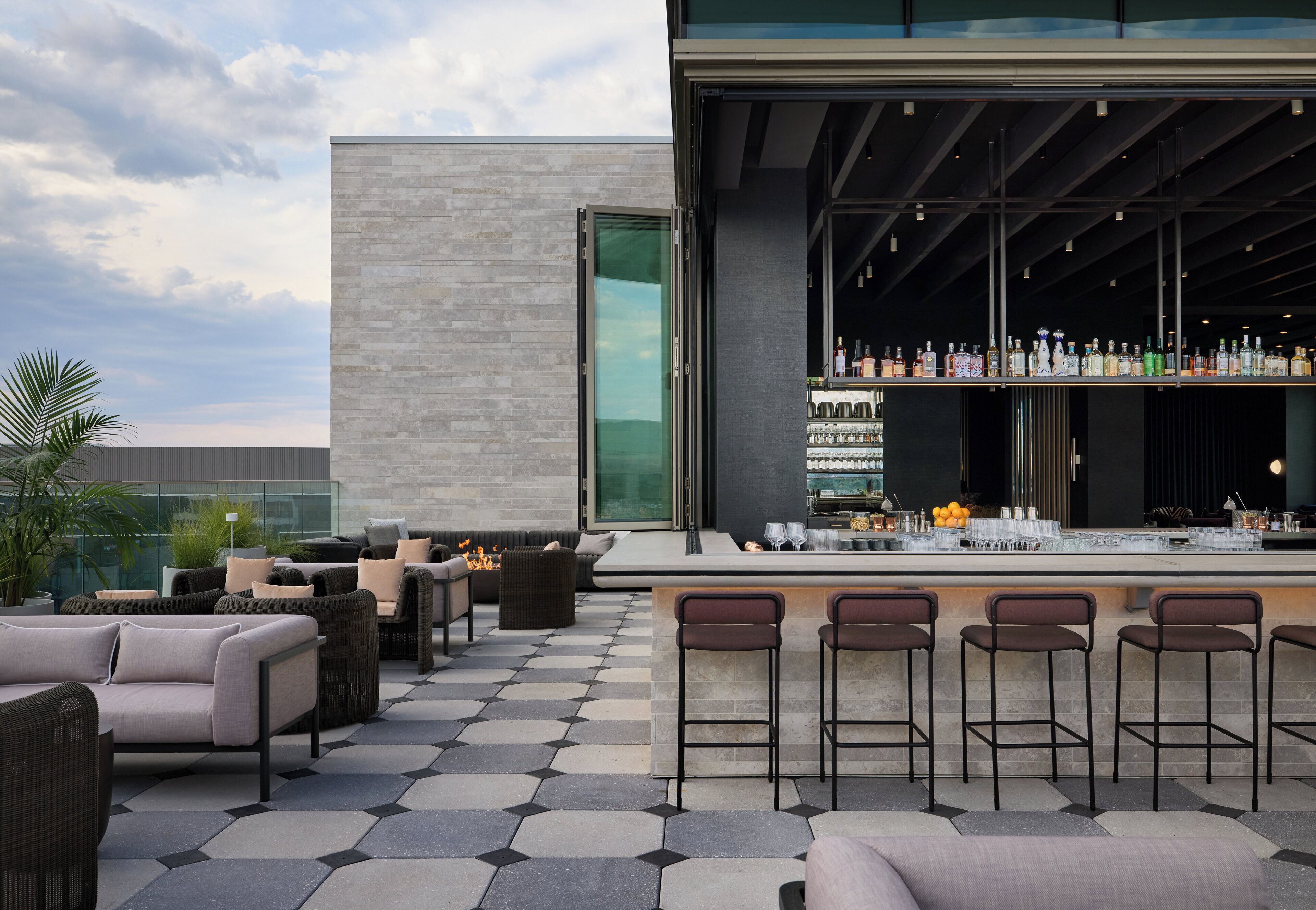 An outdoor bar area with seating and a bar stocked with bottles.