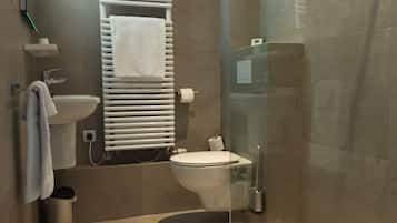 Un baño moderno con cabina de ducha de vidrio, inodoro, lavabo y toallero.