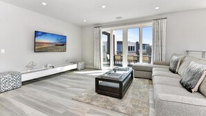 A modern living room with a sofa, a coffee table, and a TV on a white wall.