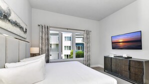 A modern hotel room with a large bed, a flat-screen TV, and a view of the outside.