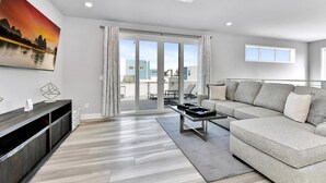 A modern living room with a grey sofa, a coffee table, and a painting of a sunset over water.