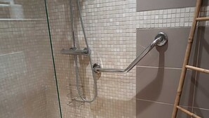 Ein Duschbereich mit Glasabtrennung, einer Haltestange und einer Bambusleiter.