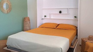 Ein modernes Schlafzimmer mit Bett, Kopfteil, Wandregal und dekorativem Spiegel.