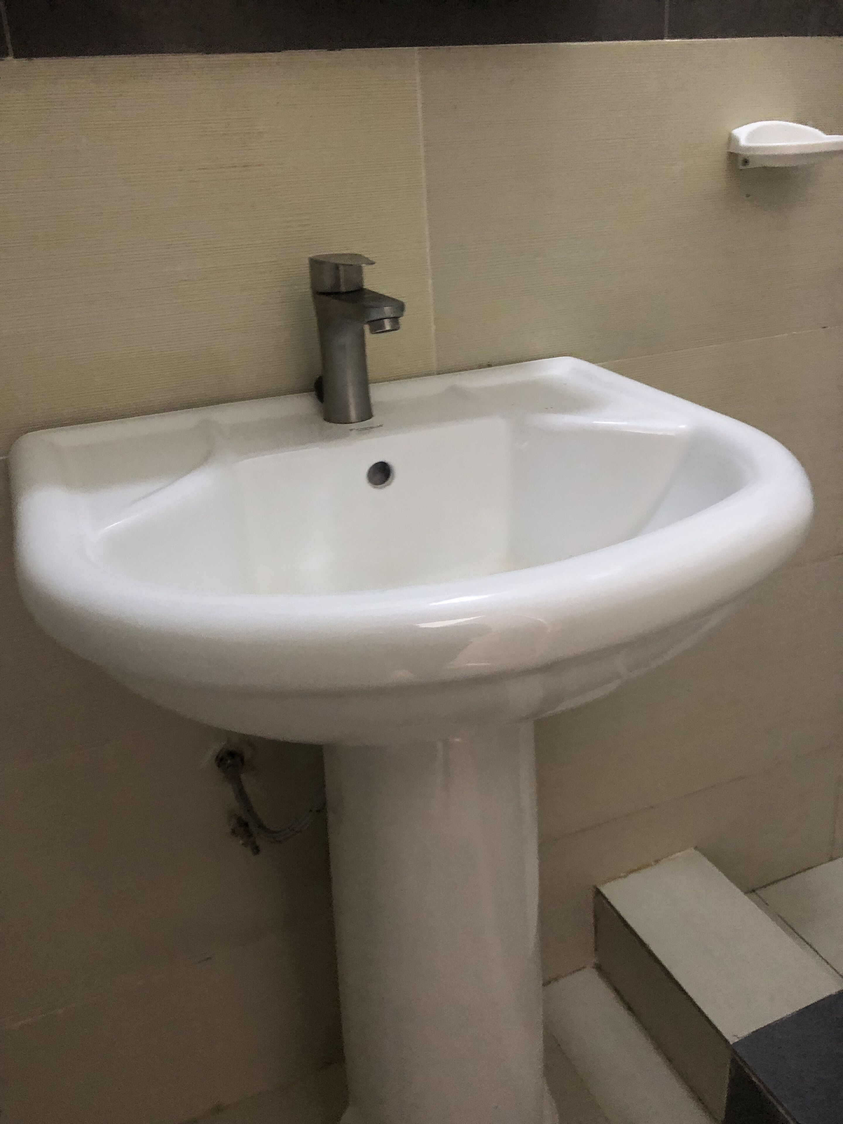 A white pedestal sink with a single faucet in a bathroom.
