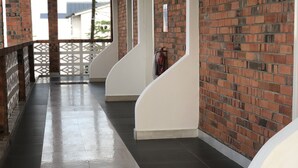 A corridor with brick walls, white railings, and a tiled floor.