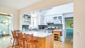 Una cocina con una isla central, sillas de madera y una estufa.