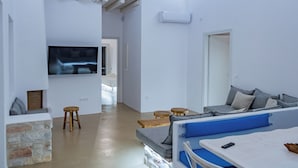 A modern living room with a sofa, coffee table, and a TV mounted on the wall. - Aegean Feelings (Paros)