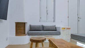 A modern living room with a grey sofa, wooden stools, and a brick accent wall. - Aegean Feelings (Paros)