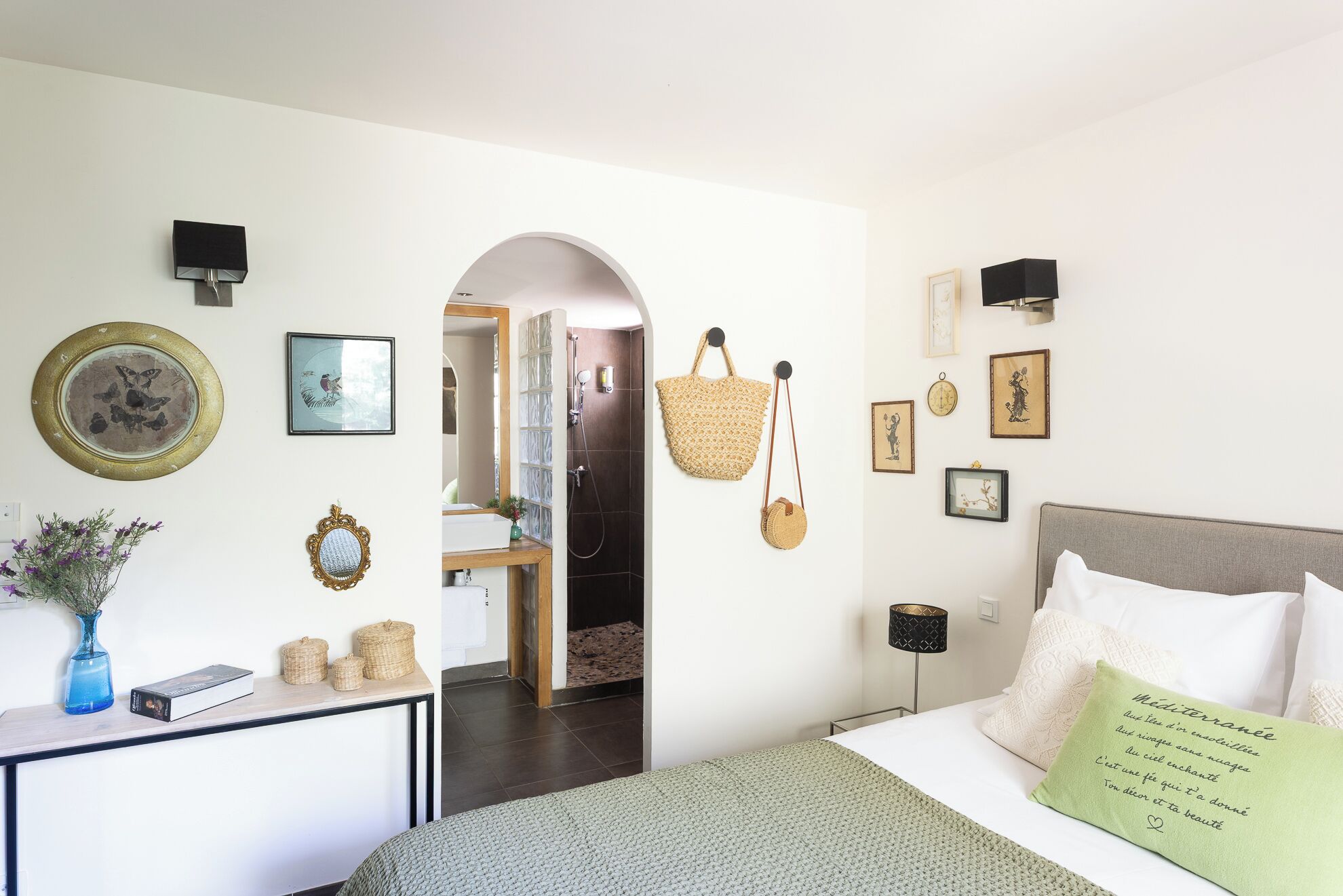 Un dormitorio con cama, lámpara de noche, reloj en la pared y espejo.