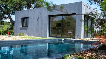A modern house with a swimming pool, large glass windows, and a minimalist design.