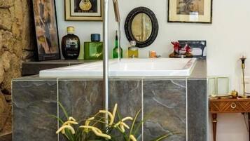 A bathroom with a stone accent wall, a sink with a mirror, and framed artwork on the wall.