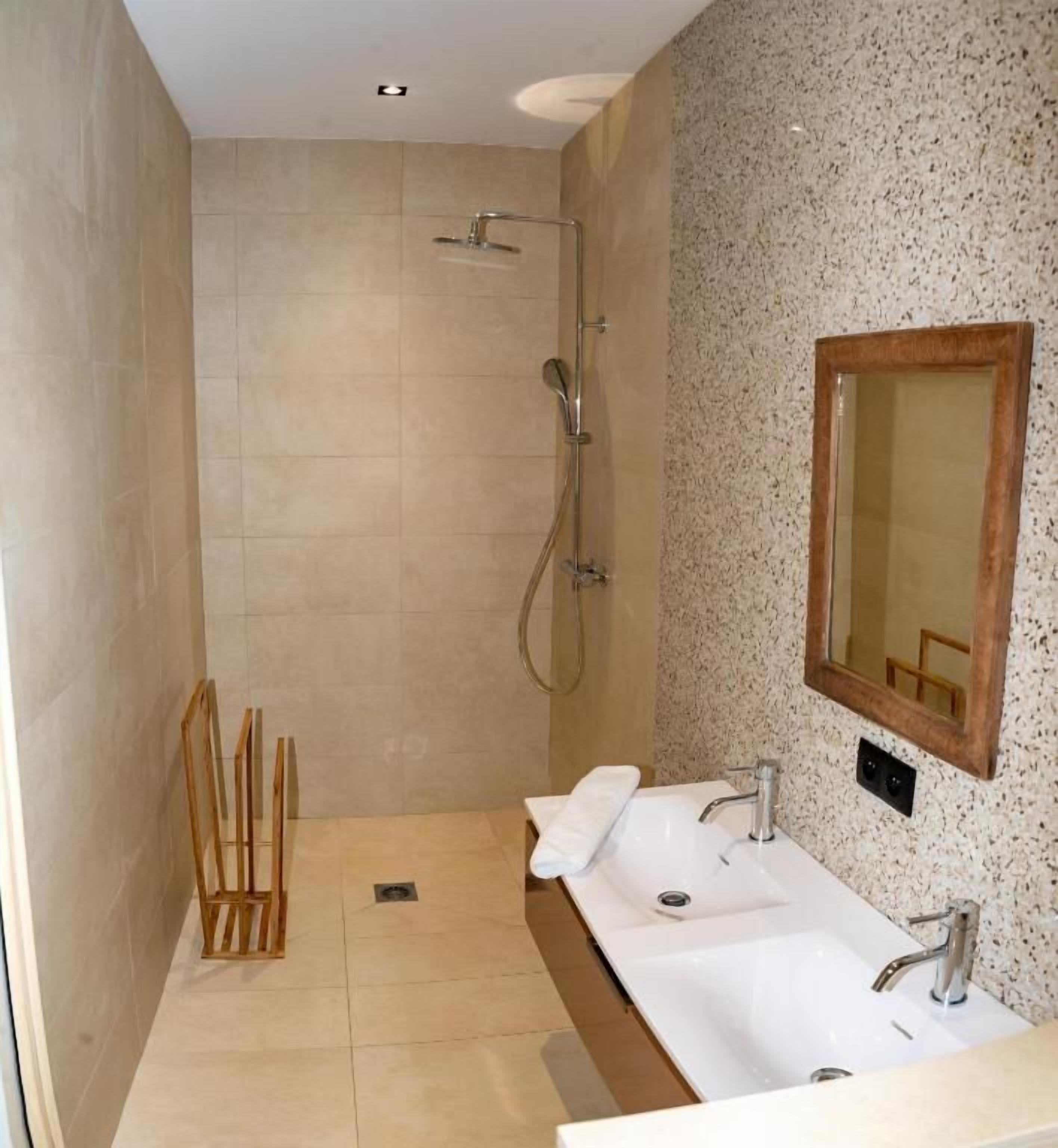 A modern bathroom with a walk-in shower, two sinks, and a large mirror.