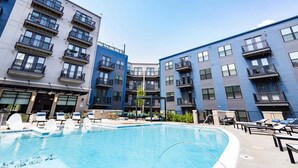Um edifício de apartamentos moderno com piscina, varandas e áreas de estar ao ar livre.