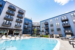 Un immeuble d’appartements moderne doté d’une piscine, de balcons et d’espaces de détente en plein air.