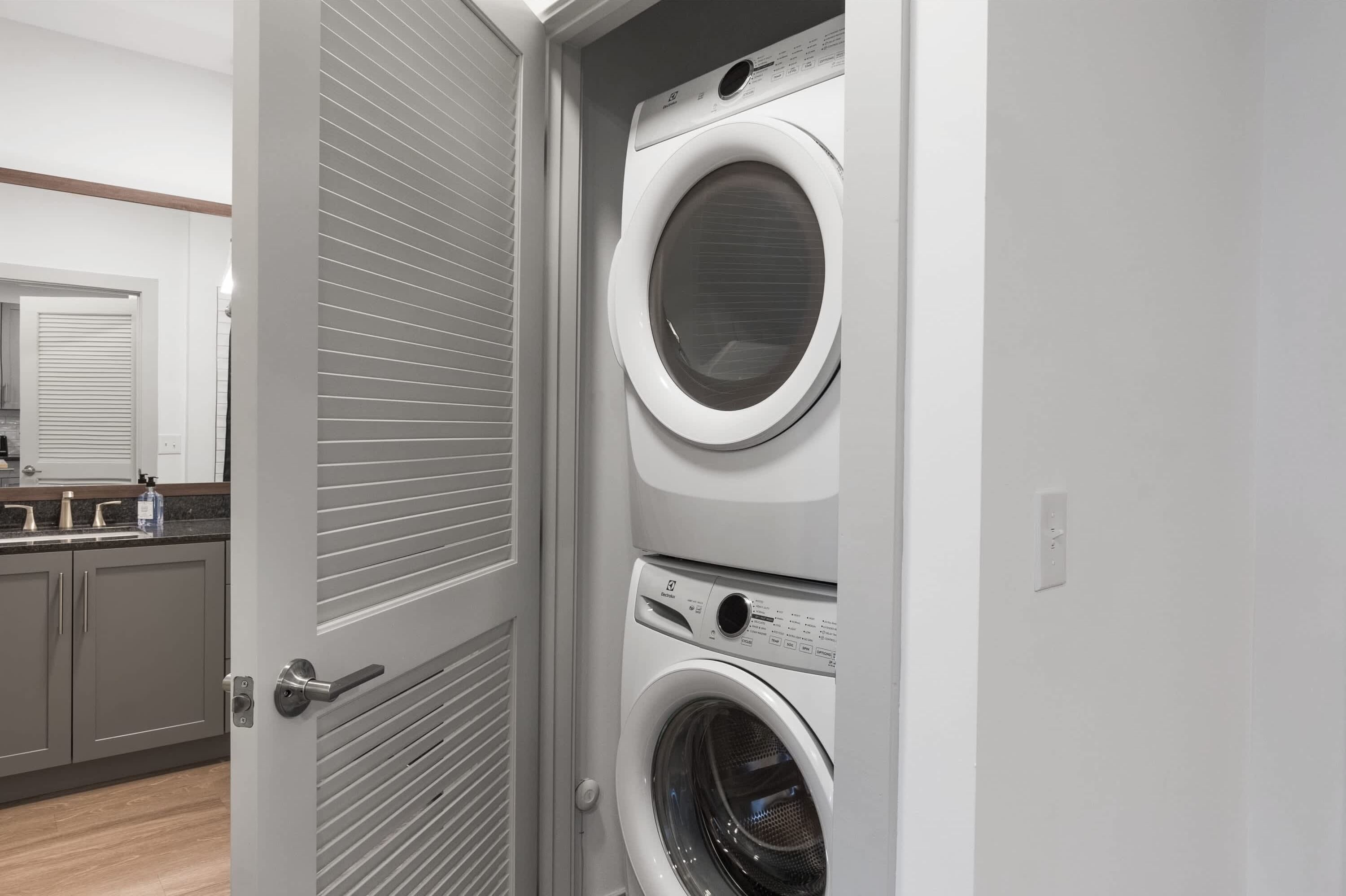 A laundry room with two stacked front-loading washing machines and a closed door.