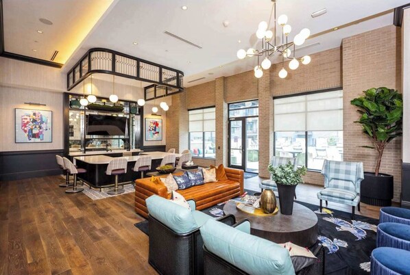 A modern hotel lobby with a kitchen area, seating arrangements, and large windows.