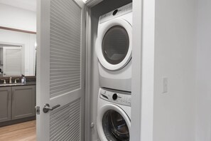 A laundry room with two stacked front-loading washing machines and a closed door.