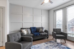 A modern living room with a grey sofa, two armchairs, and a patterned rug.