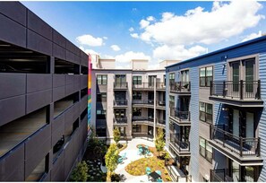 A multi-story building with balconies, a courtyard with seating, and a visible parking structure. - Shop & Dine Nearby! Cozy Cincy Condo Awaits (Cincinnati)