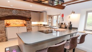 Een moderne keuken met een centraal kookeiland, stenen details en barstoelen.