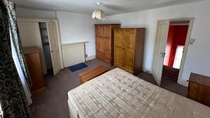 A bedroom with a bed, a wardrobe, a chest of drawers, and a door leading to another room. - Walton Apartment (London)