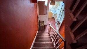 A staircase with a handrail leading to a room with a window and a sink. - Walton Apartment (London)