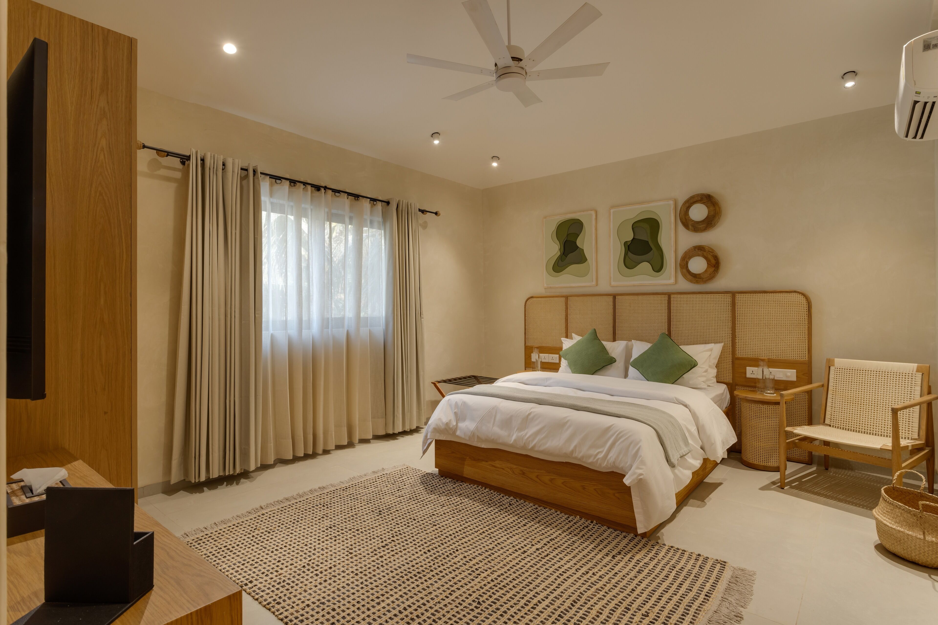 A bedroom with a bed, a chair, a desk, a ceiling fan, and a window with curtains.